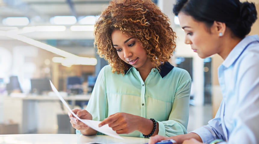 Two office workers reviewing a printed out resume