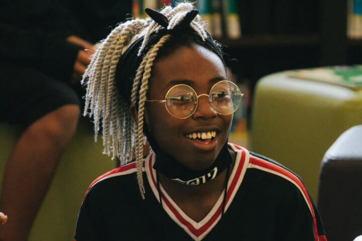 A smiling teen in glasses and a sporty sweater