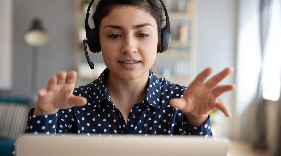 Adult at laptop with headphones and mic