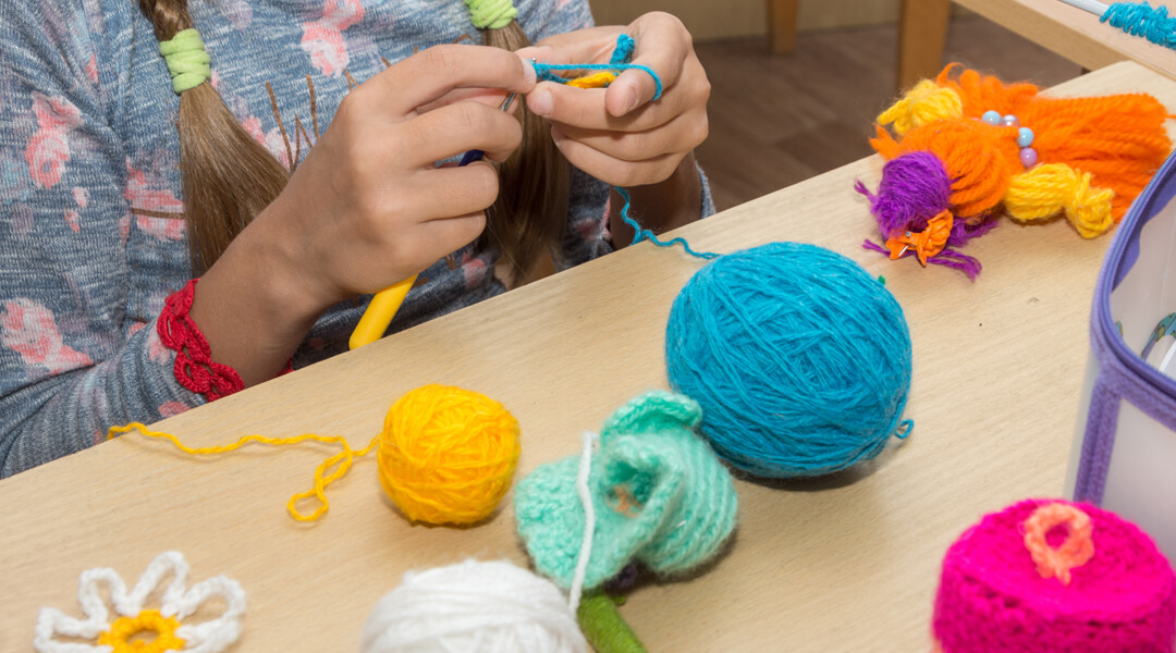 Teen crocheting at table