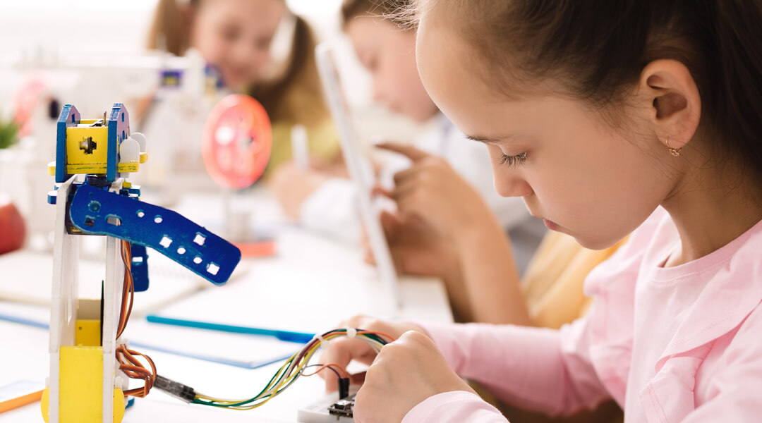 Kids doing science experiment with small robot and wiring