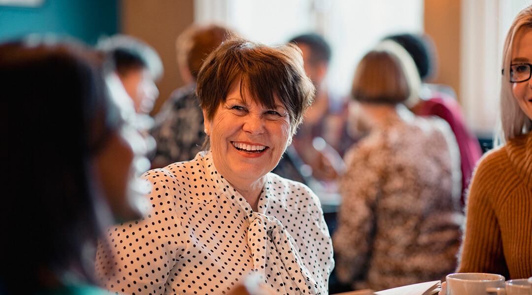 Woman laughing and smiling while sitting with friends
