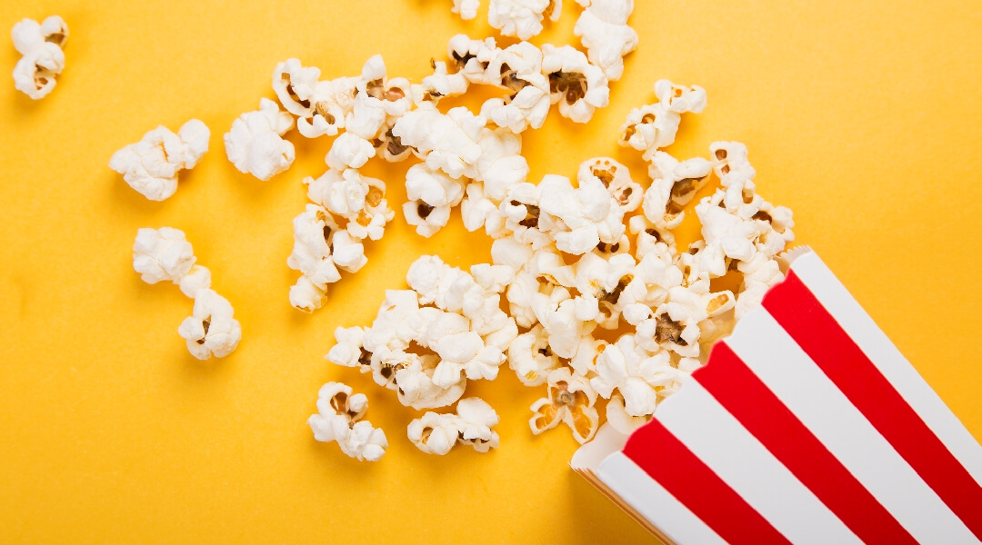 Movie theater popcorn container spilled across a yellow background