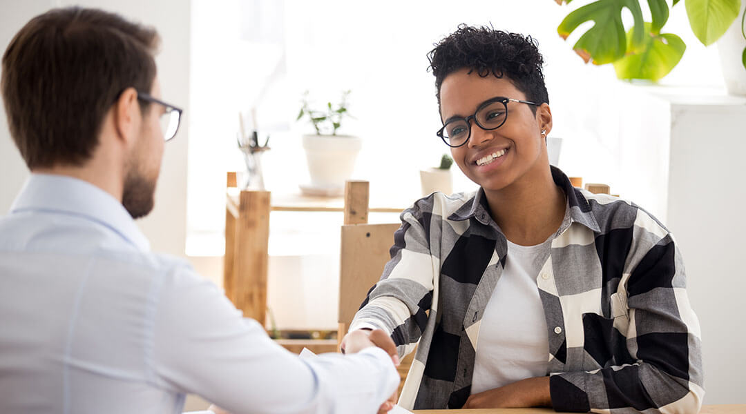 Smiling adult applicant shaking hands at the end of a meeting