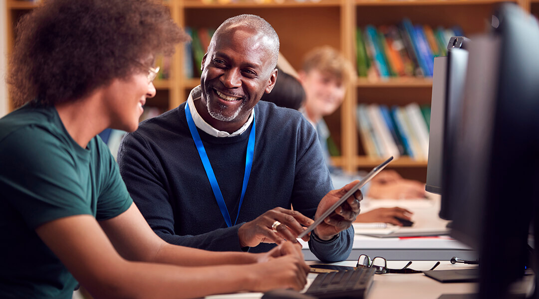 A librarian assists a young adult on the computer.