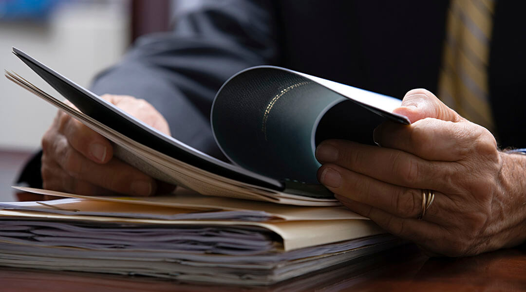 Close up of hands perusing through a stack of documents.
