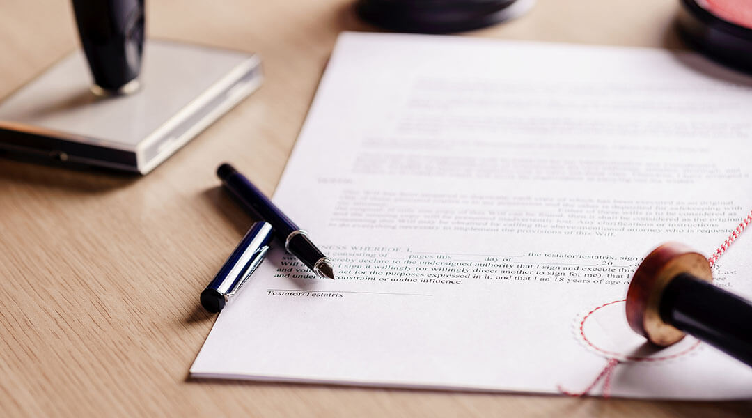 A pen and notary stamp rest on top of an unsigned contract.