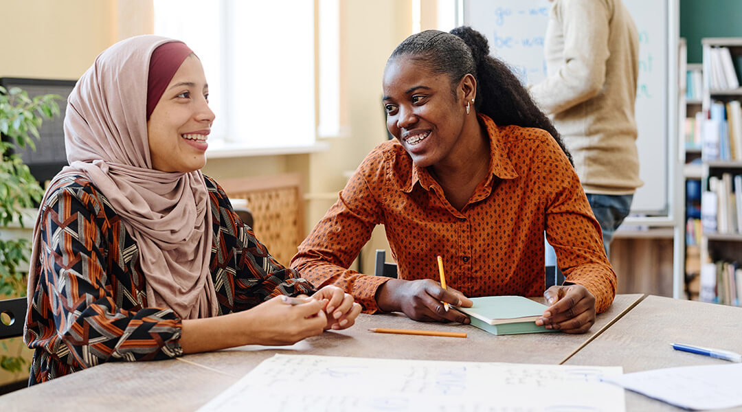 Two young adults having fun chatting about something during a language class.