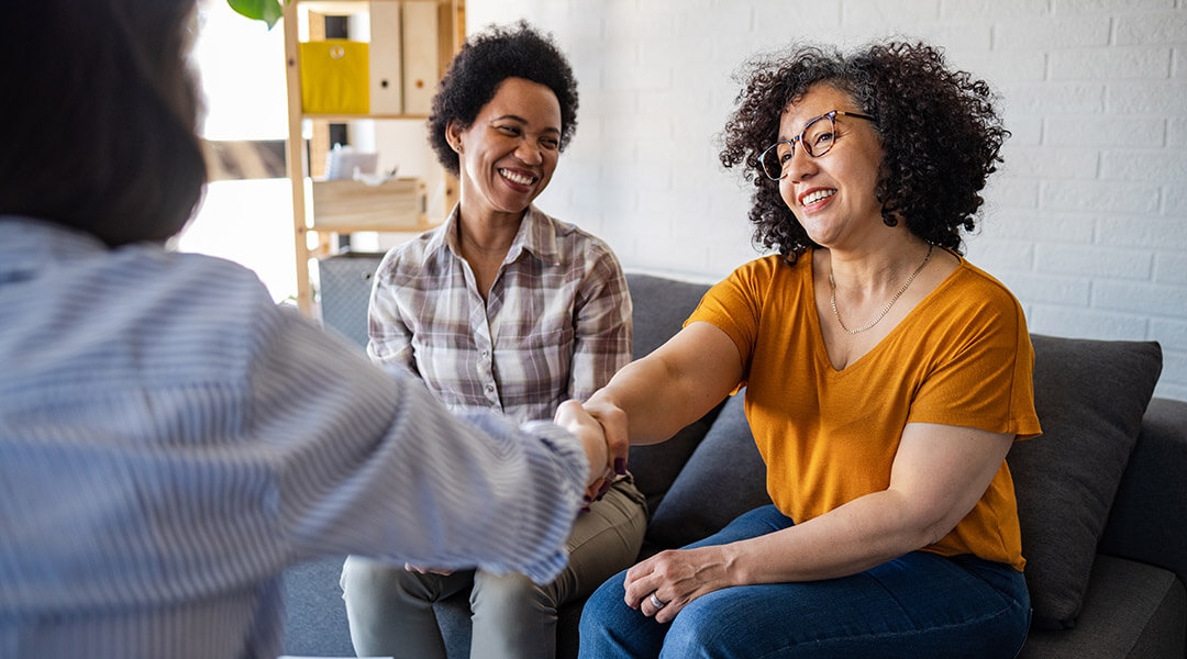 A couple shaking hands with the person they are meeting with.