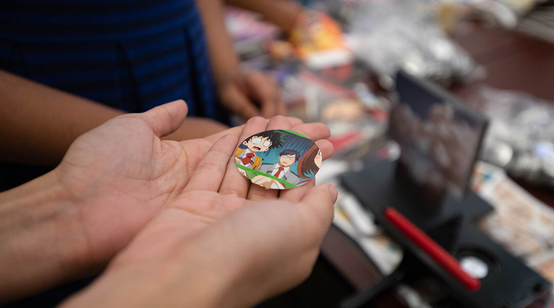 Close-up of two hands holding a circular piture from an anime as teens participate in the button-making activity at the 2018 Teen Awards in the Carnegie Library of Pittsburgh's Main Library on Saturday Aug. 11, 2018, in Oakland.