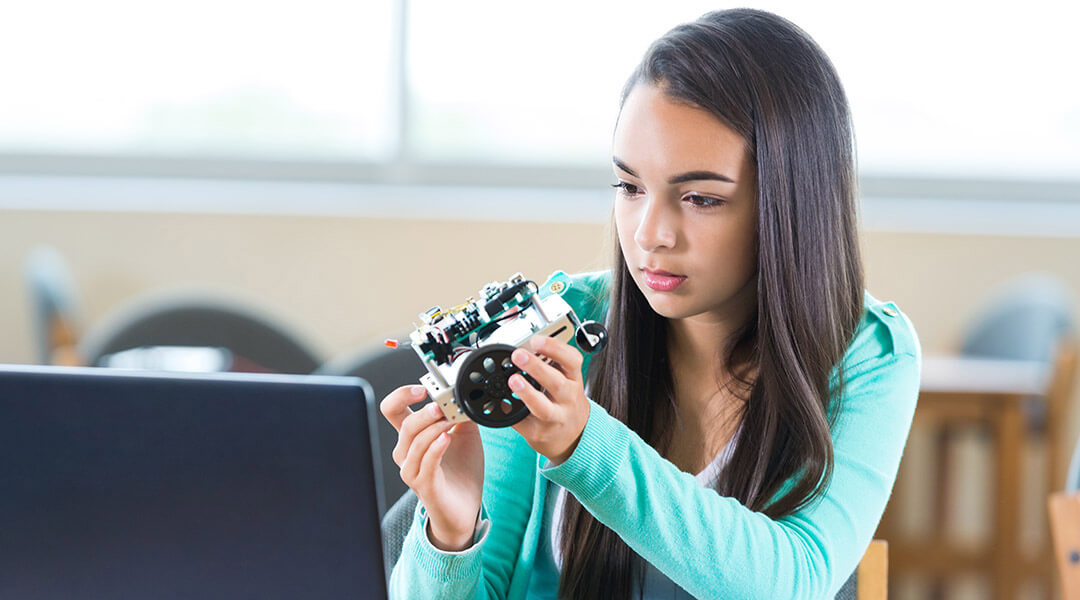 A high school student in works on robot in after school engineering club.