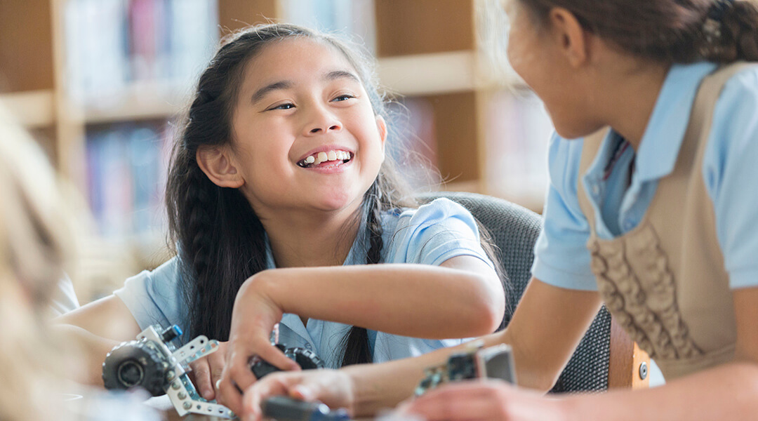 Happy elementary students build a robotic vehicle together.