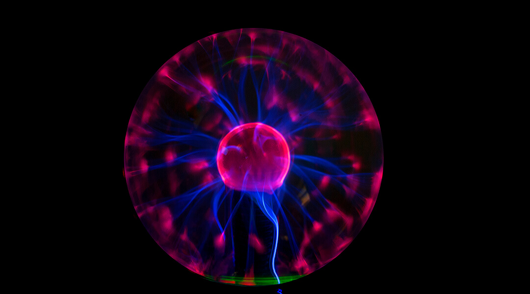 A Tesla coil crackling with electricity, pink and blue on a black background.