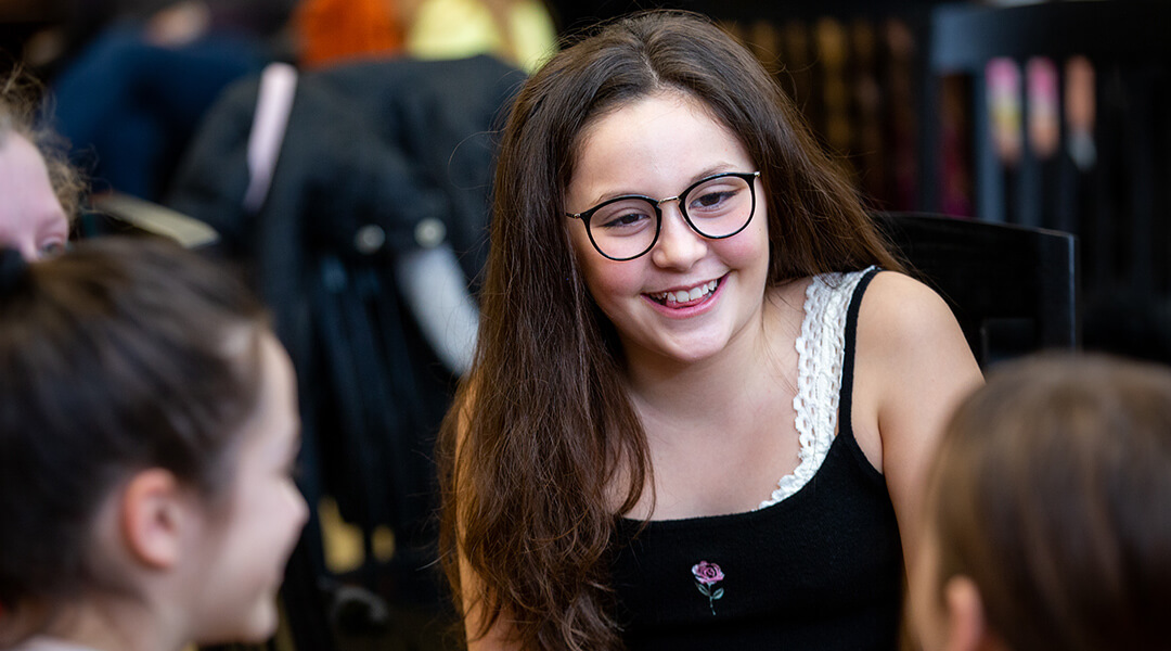 A tween smiles at friends during a library program.
