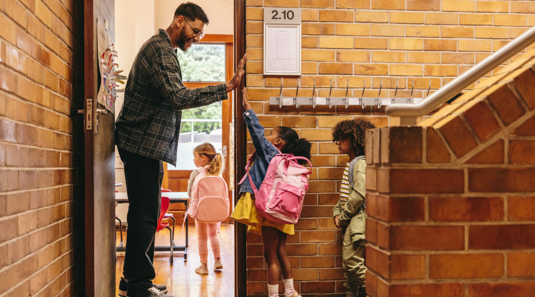 Students high fiving teacher as they enter a classroom