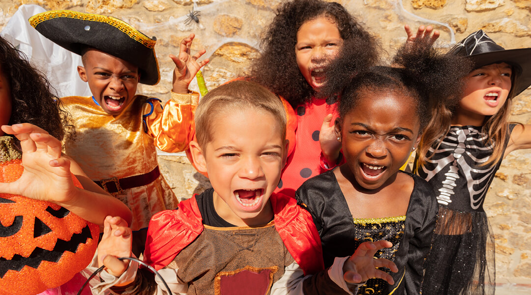 A group of children, about 8, wearing costumes, screaming at the camera.