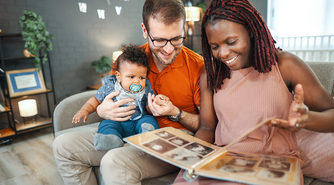 A couple and their baby look through a family photo album together.