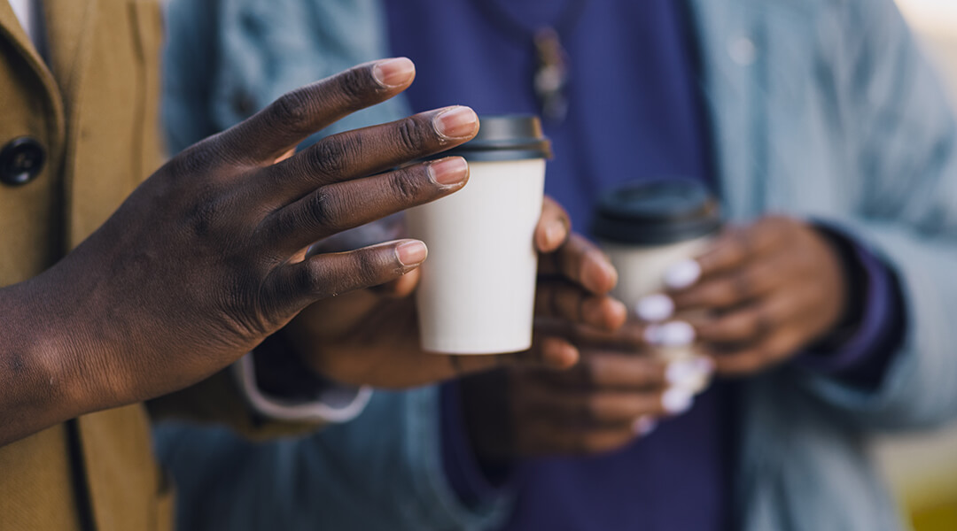 Unidentifiable couple drinking coffee while having a walk on a sunny day.