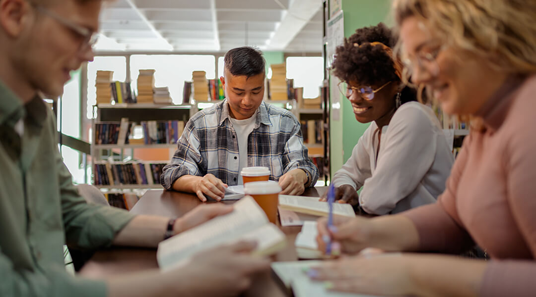 Young university students writing in library.