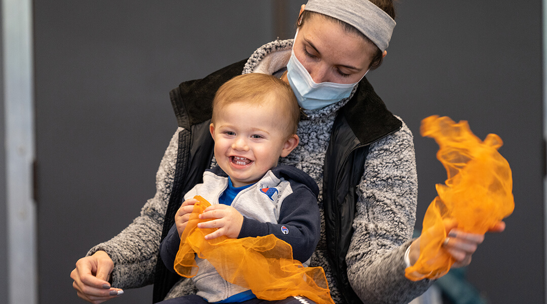 A caregiver and young child, about two, play with scarves during storytime.