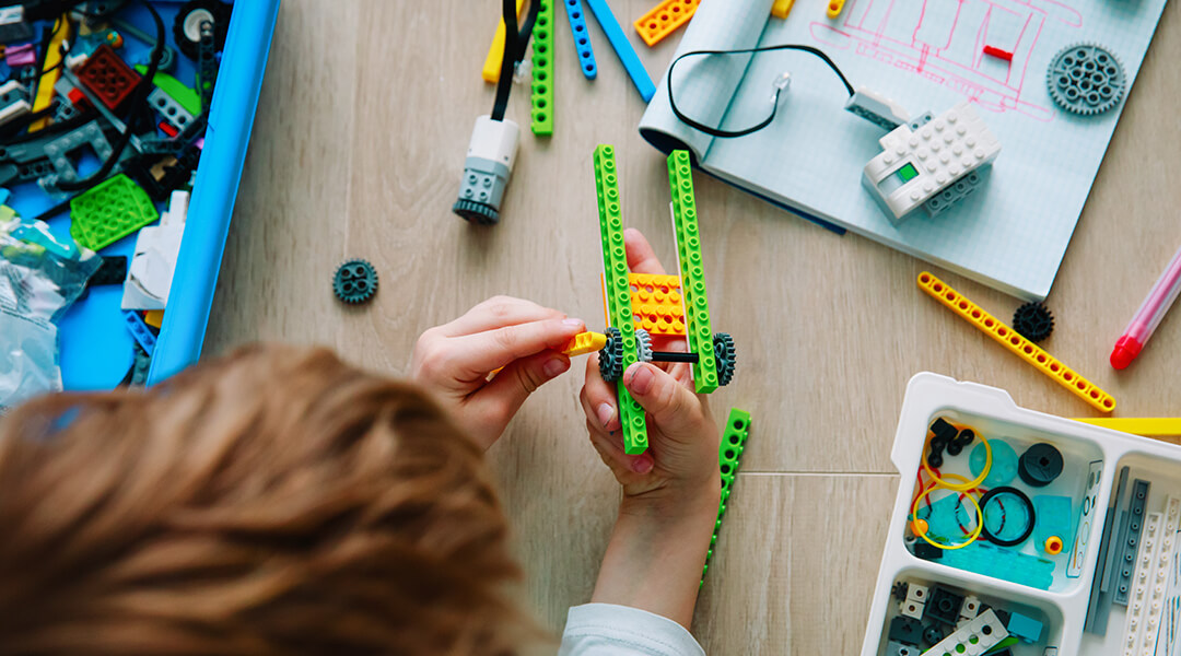 Overhead view of a child assembling a robot using legos.