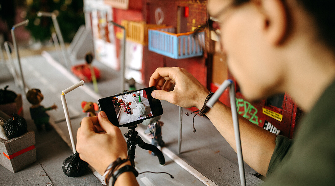 A stop motion animation director sets a scene to film on their phone.