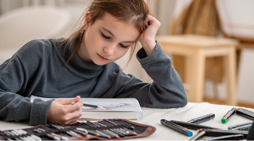 A teenager shades a drawing in a sketchbook.