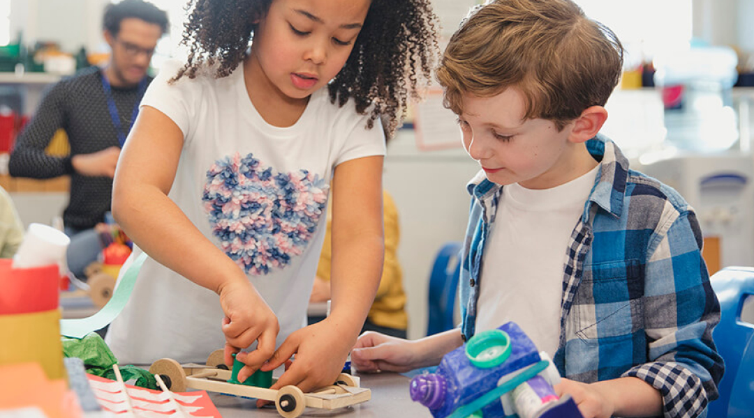 Two elementary school students build a contraption.