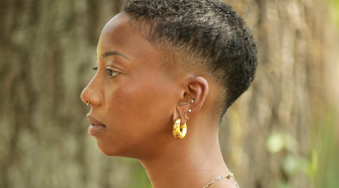 Profile of a Black woman with short hair and gold accessories.