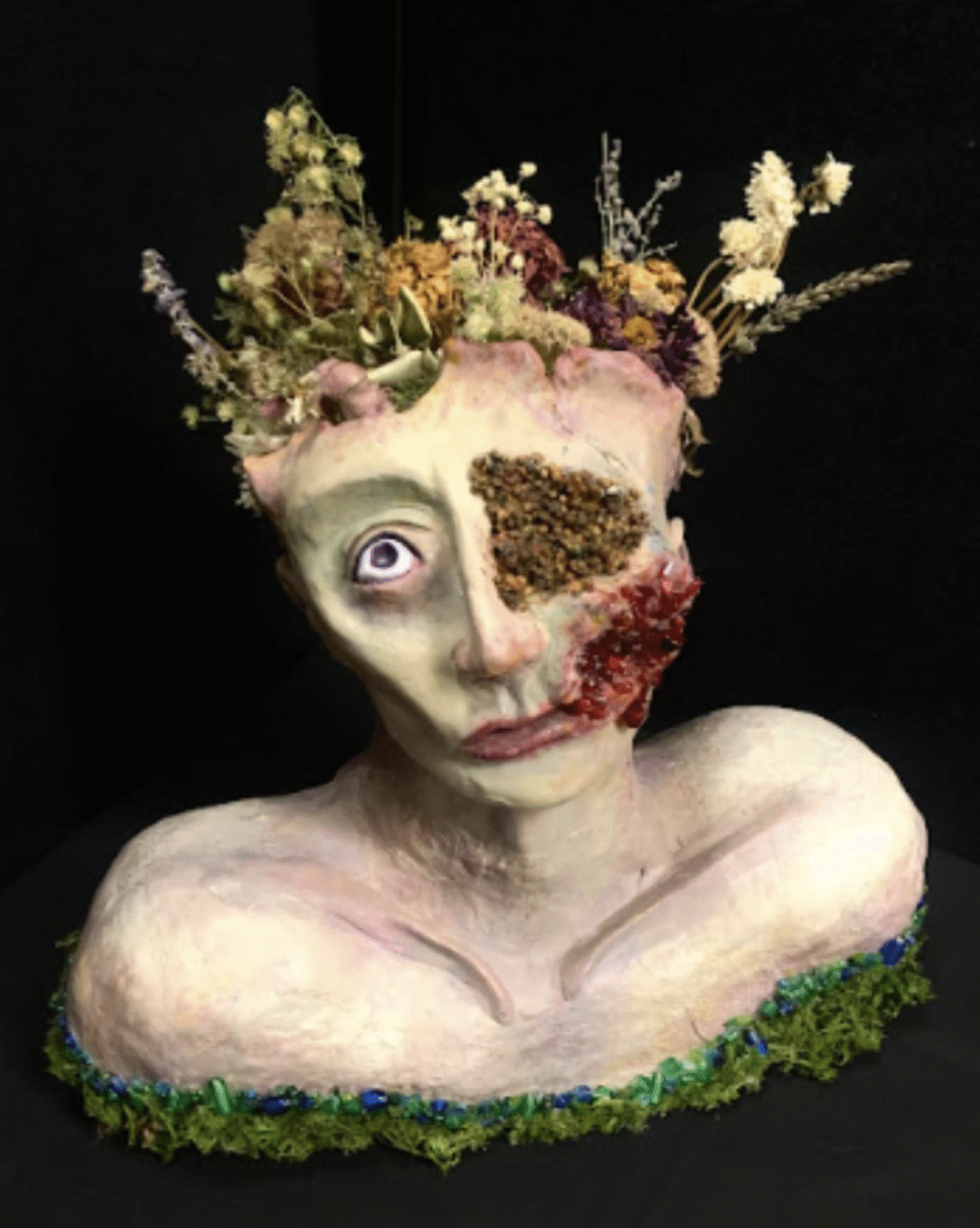 By Hadly Webb. Bust sculpture of a person whose flesh is decomposing; the top of their head blooming flowers.
