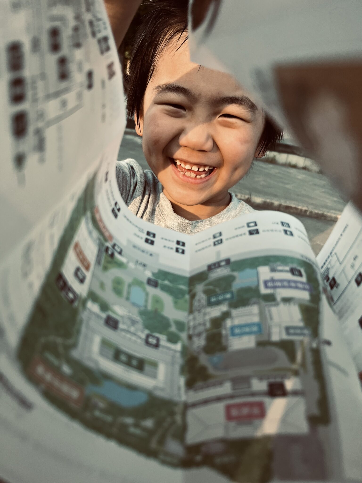A smiling child framed by the open pages of a newspaper.