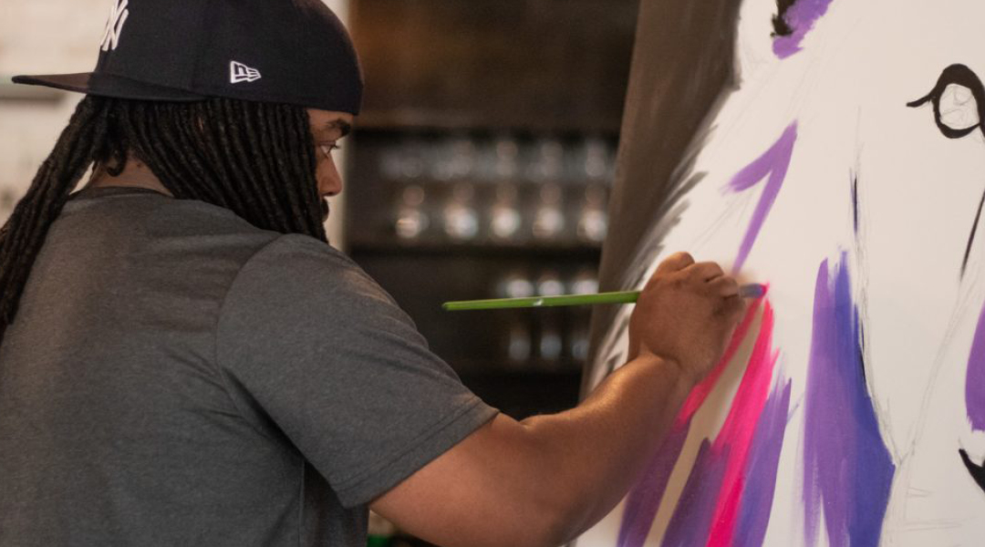 Artist Cue Perry paints at an easel.