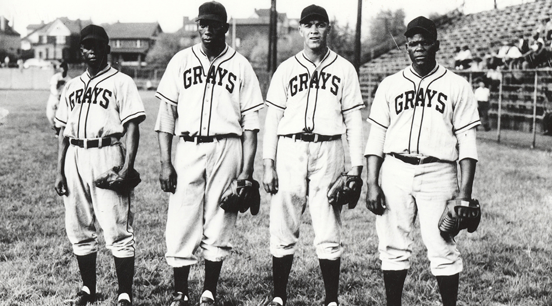Black and white photo of four baseball players in Grays uniforms.