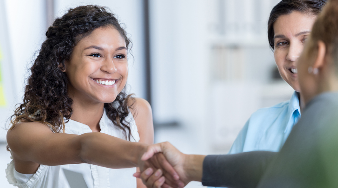 A young adult shakes hands with an interviewer.