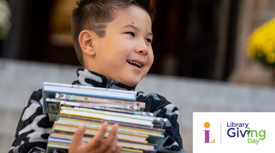 Little boy carrying a stack of books in front of Main Library