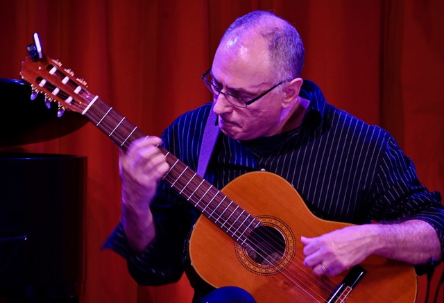 Photo of John Marcinzyn. A man playing an acoustic guitar.