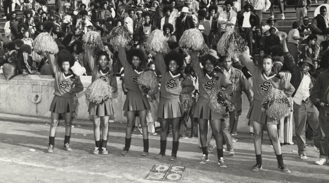 A black and white photograph of Black cheerleaders at a sporting event.