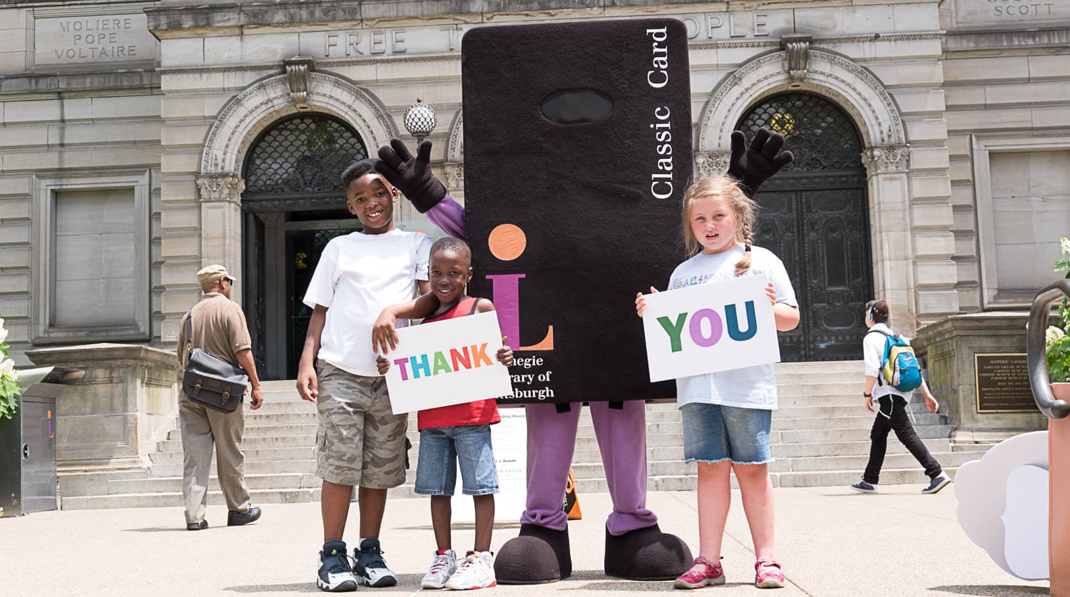 Children in front of Carnegie Library of Pittsburgh – Main (Oakland) with a library card mascot