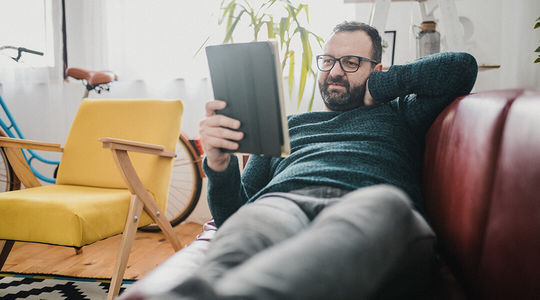 adult man reading a book on the couch