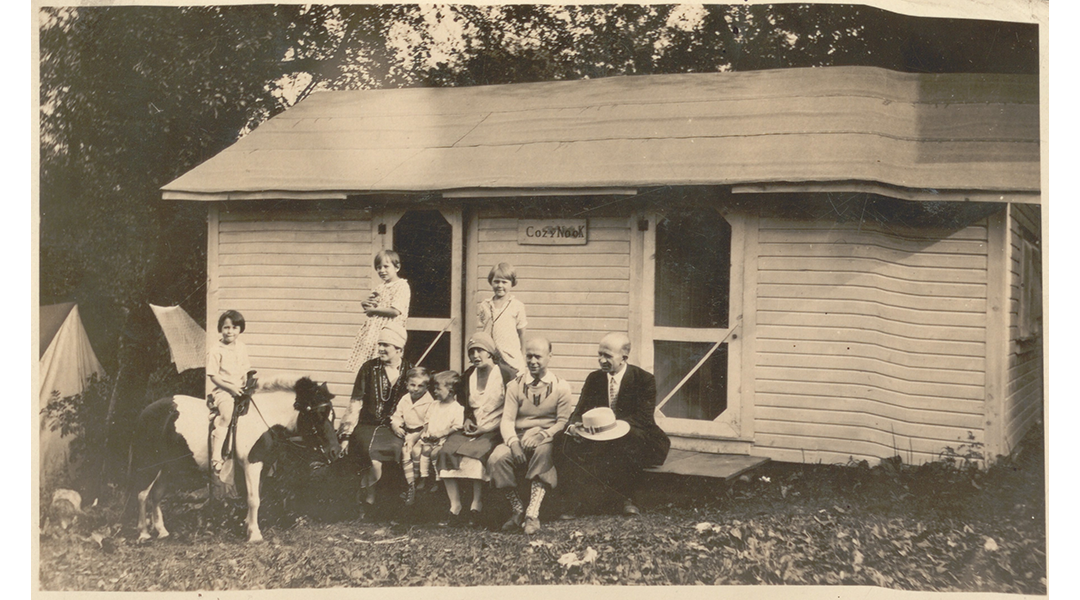 Vintage photo of a group of people sitting in front of a vacation cottage