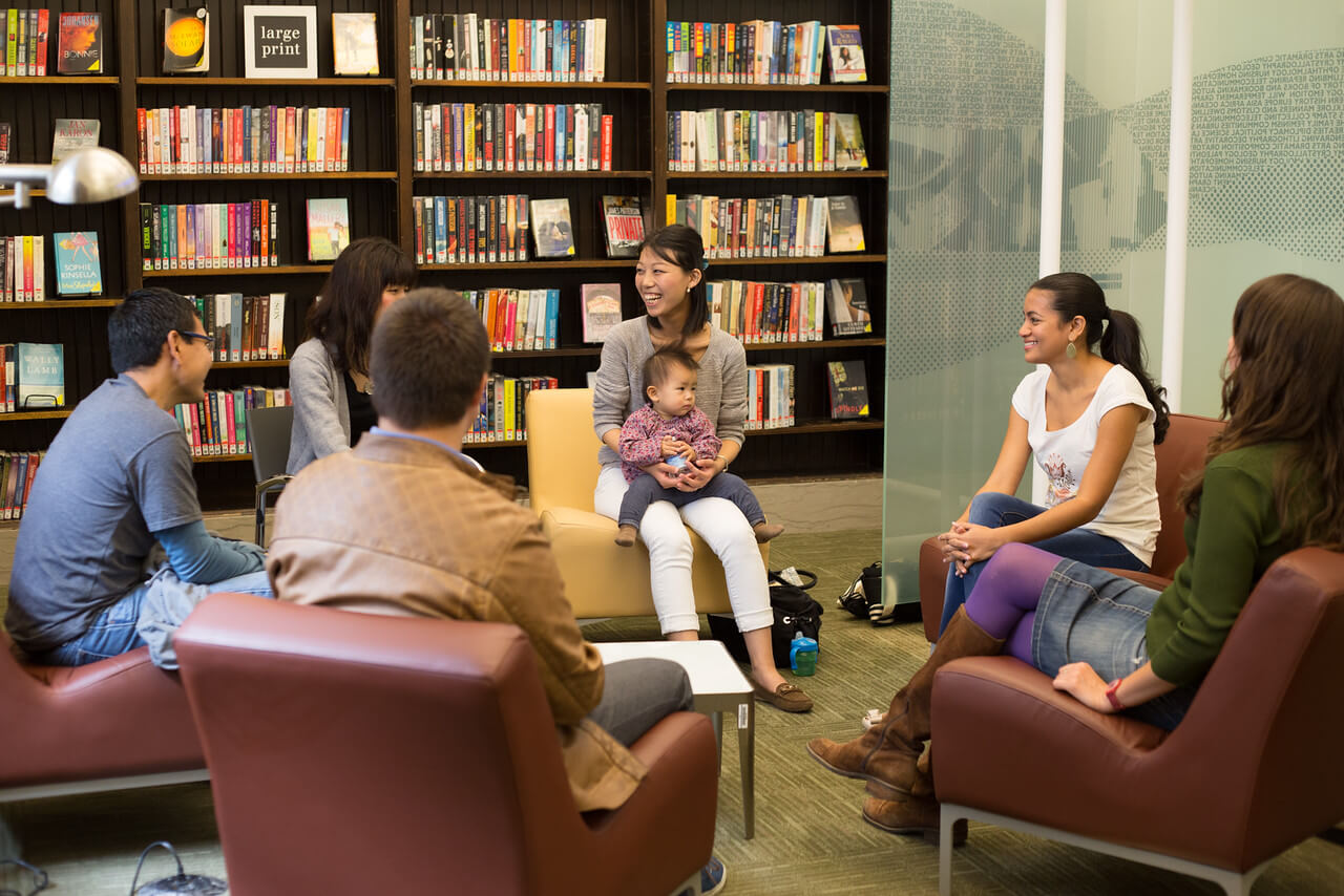 A language learning group speaks to each other in a circle in the library