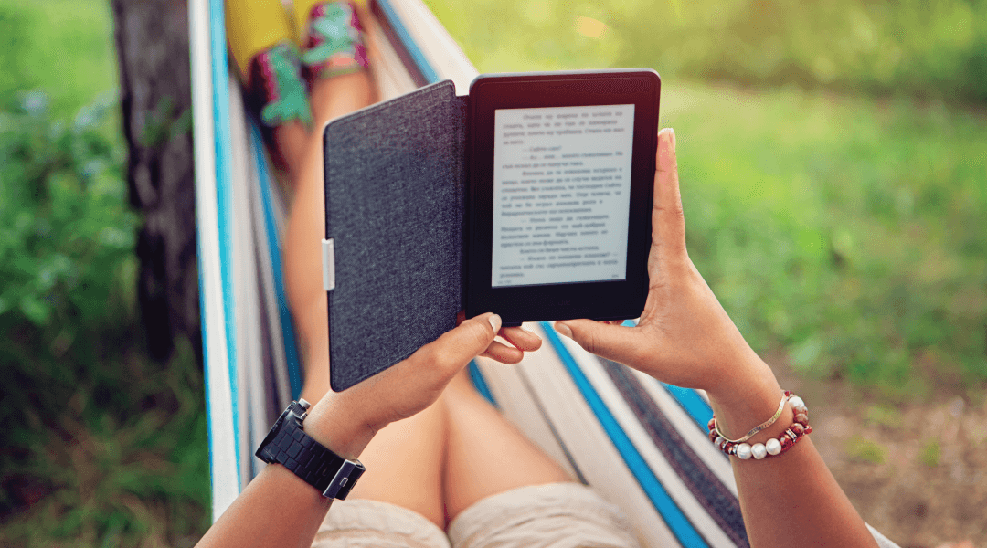 A person lying in a hammock reading an ebook on their tablet
