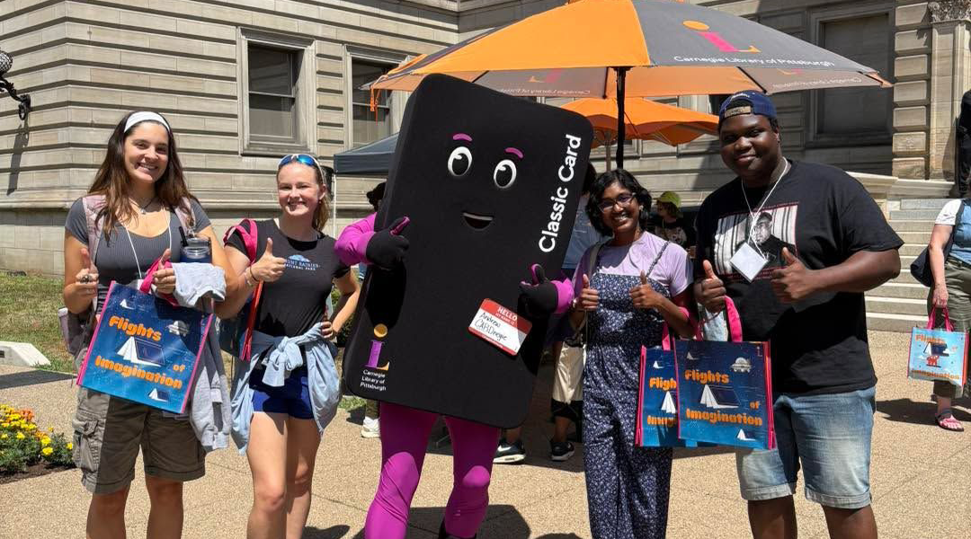 The Library Card mascot posing for a photo with other library goers.