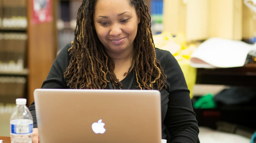 A woman smiles at her laptop