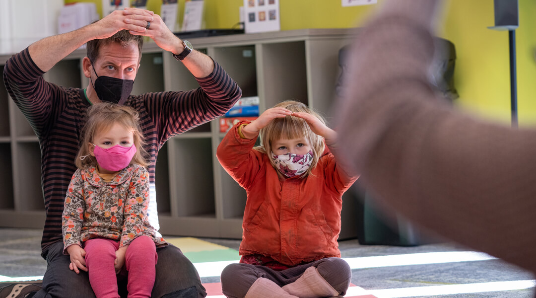 An adult and two children participate in a movement activity