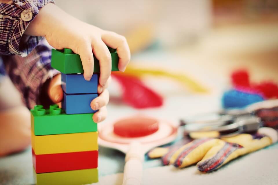 A Child's hands play with stacking bricks.