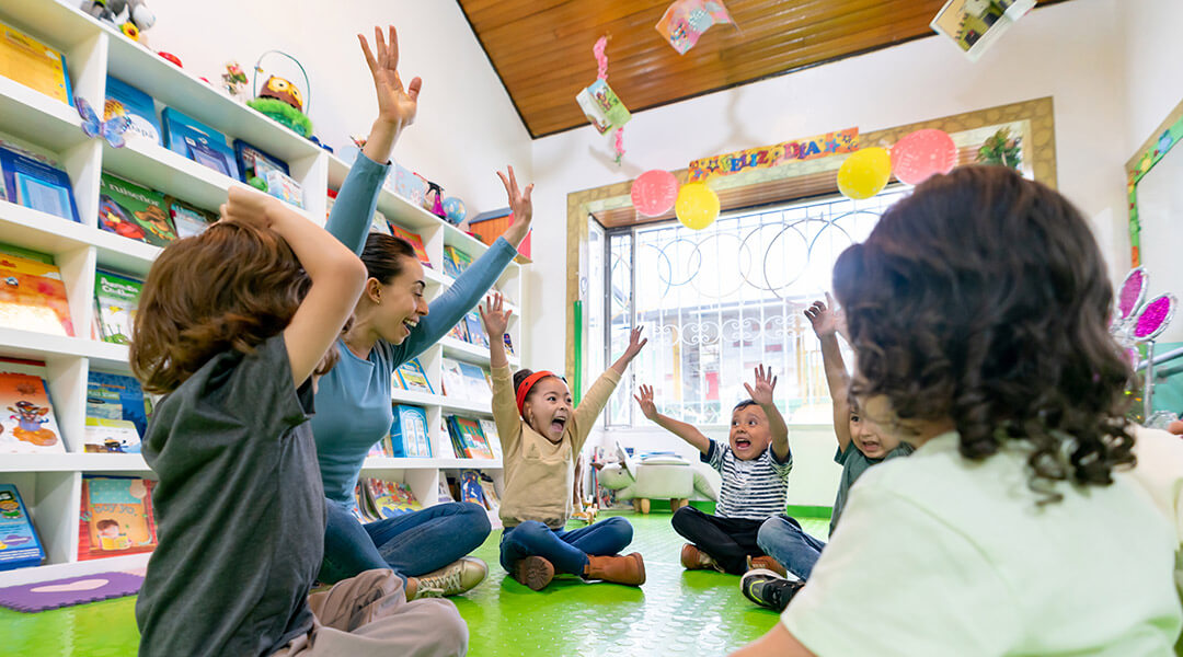 A group of kids raising their hands during a storytime