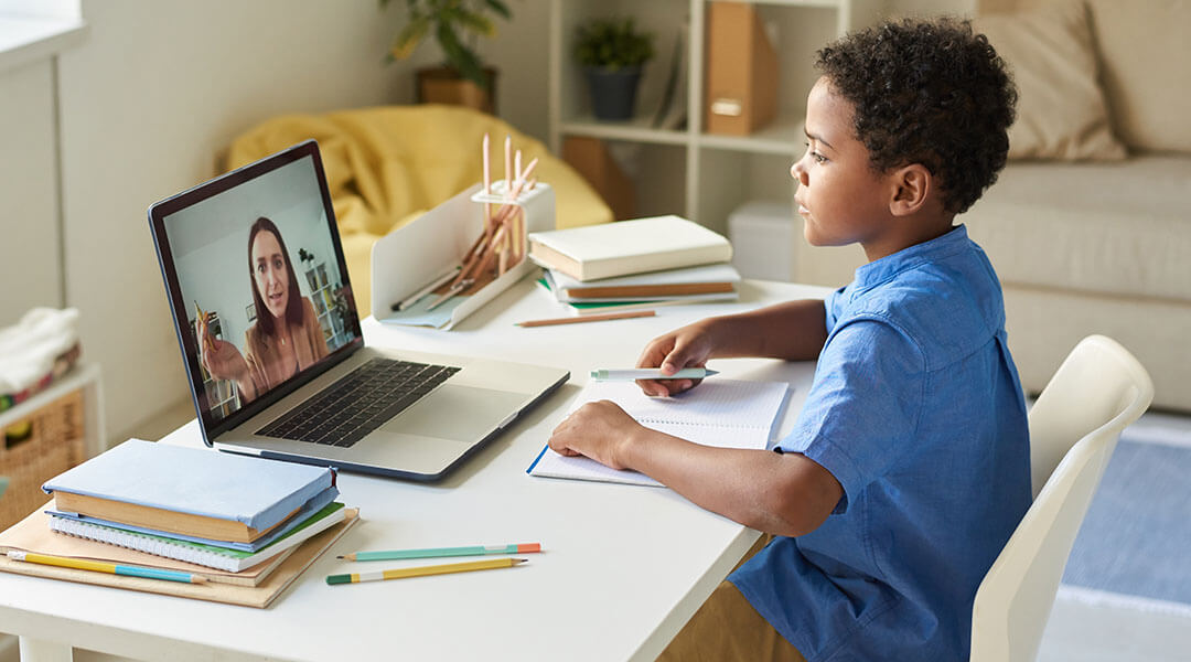 A child works with a tutor on a laptop