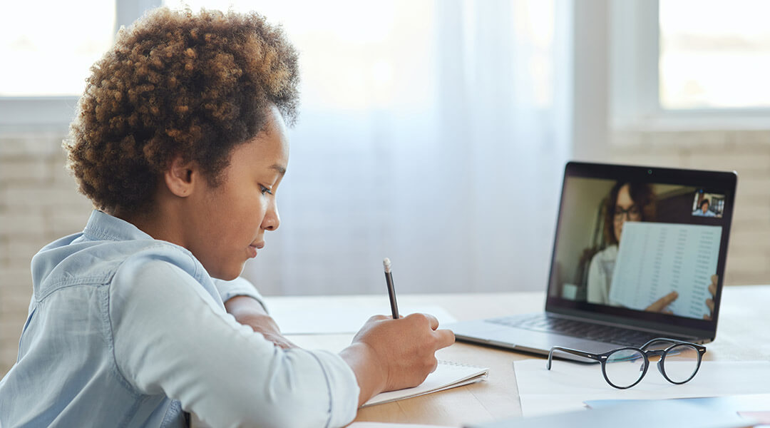 A child works on homework in front of a computer