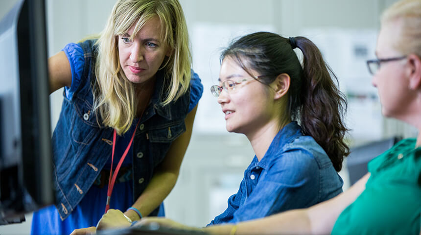 Three people looking at a computer monitor while one points